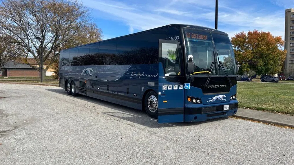 Greyhound.com bus with dark blue and chrome plated accessories waiting for passengers in a parking lot, ready to take them on a comfortable and safe journey.