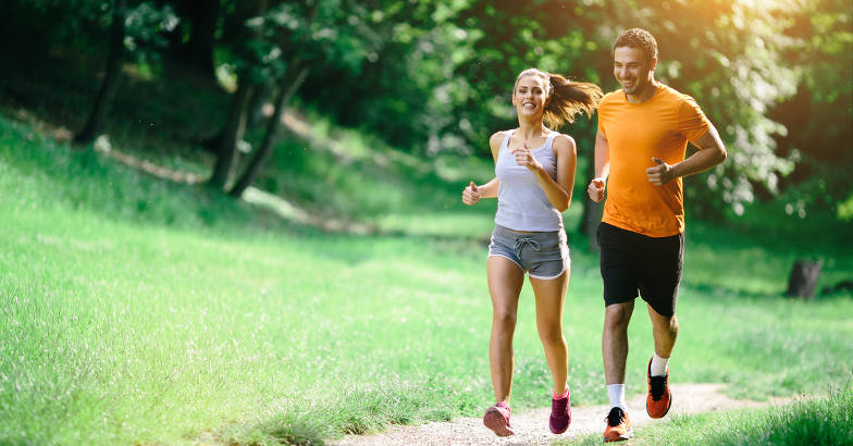 A guy and a girl running in the park.